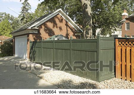 Picture - GARAGE: red brick with Federal style molding, green wooden fence, gravel and concrete in alleyway. Fotosearch