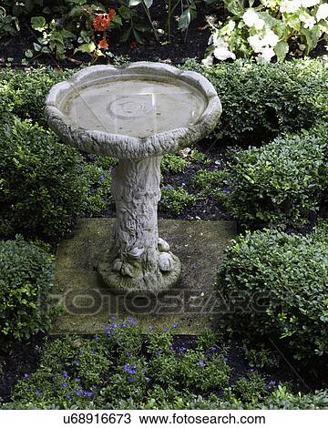 Stock Image - GARDEN: birdbath in center of boxwood hedge parterre. Fotosearch