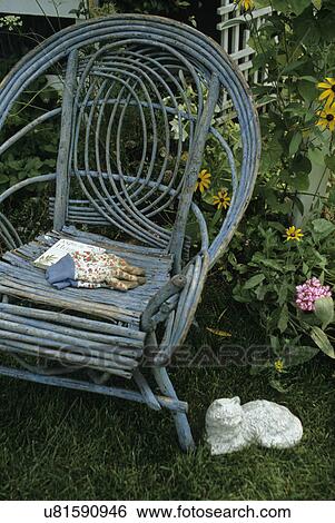 Stock Photograph - Gardens: Antique willow chairs in front of a white trellis w/ morning glories and black-eyed susan's, work gloves in seat of chair. Several angles.. Fotosearch