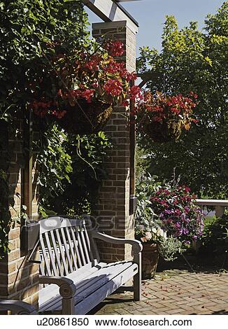 Stock Image - GARDENS: Brick patio with brick columns, pergola, hanging baskets, wooden bench, climbing vines. Fotosearch