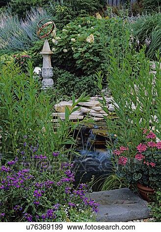 Stock Photo - Gardens: New American garden style, reflecting pool with water fall, sundial on pedestal, geraniums, Russian sage, and others surround area. . Fotosearch