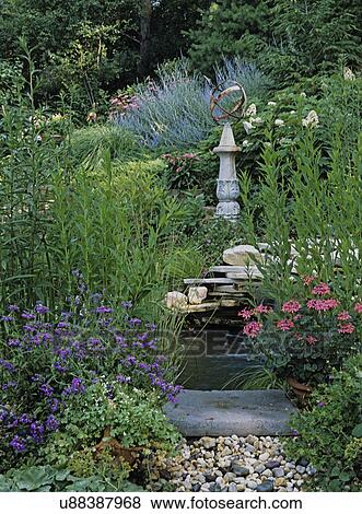 Gardens: New American garden style, reflecting pool with water fall, sundial on pedestal, geraniums, Russian sage, and others surround area. different view with more stone peoples in foreground, less waterfall showing, Lady's Mantle in foreground View Large Photo Image Stock Photo - Gardens: New American garden style, reflecting pool with water fall, sundial on pedestal, geraniums, Russian sage, and others surround area. different view with more stone peoples in foreground, less waterfall showing, Lady's Mantle in foreground. Fotosearch