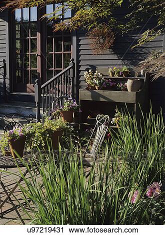Gardens: Red brick patio area, potting station on the right. Lots of potted flowers. Clapboard house. Metal table and chair. Surrounded by garden. View Large Photo Image Stock Image - Gardens: Red brick patio area, potting station on the right. Lots of potted flowers. Clapboard house. Metal table and chair. Surrounded by garden. . Fotosearch