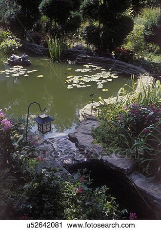 Stock Image - GARDENS: Water flows from pond to streambed before recirculation, 1930's built pond and rock gardens, lantern, lily pads, lush gardens, shell sculpture . Fotosearch