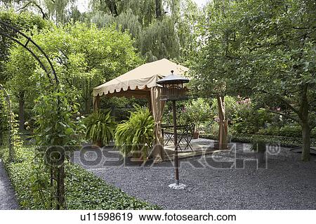 Stock Photo - GAZEBOS: Garden, patio angled view of fabric gazebo, two large Boston ferns. Fotosearch
