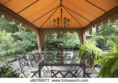GAZEBOS: Garden, patio, fabric gazebo, chandelier, rectangular dining table, Boston ferns garden surrounds View Large Photo Image Stock Photo - GAZEBOS: Garden, patio, fabric gazebo, chandelier, rectangular dining table, Boston ferns garden surrounds. Fotosearch