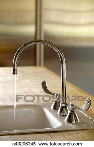 Stock Photography - Gooseneck faucet with running water; Carpinteria; California; USA. Fotosearch