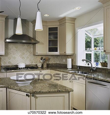Stock Image - Granite counters in kitchen with triangle work area, tile back splash with pendant lighting, window greenhouse. Fotosearch