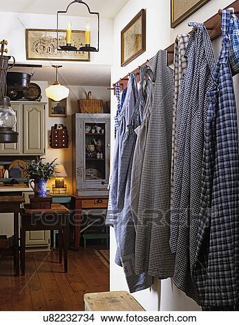 HALLWAYS: View from hallway to kitchen, checked aprons hang on peg hooks, pine wood floors, storage cupboards, farm tables, pendant light, country style. View Large Photo Image Picture - HALLWAYS: View from hallway to kitchen, checked aprons hang on peg hooks, pine wood floors, storage cupboards, farm tables, pendant light, country style. . Fotosearch