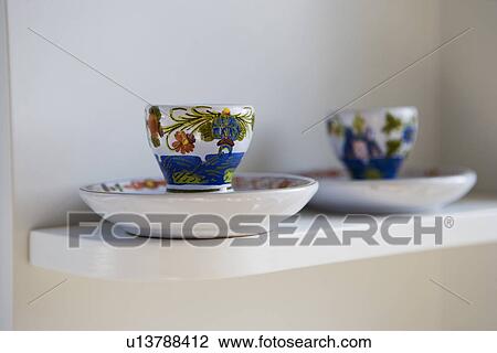 Stock Image - Hand painted teacups and saucers on shelf; Hollywood; California; USA. Fotosearch