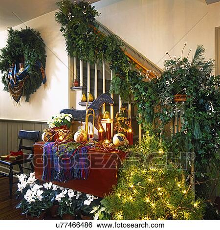 HOLIDAYS: Display of gorgeous Christmas decorations, garland winds around banister, tallow berries, small lit tree, table with red candles, wooden folk art horse, cranberry garland, plaid cloth, white poinsettia, white cyclamen, wreath on wall. View Large Photo Image Stock Photograph - HOLIDAYS: Display of gorgeous Christmas decorations, garland winds around banister, tallow berries, small lit tree, table with red candles, wooden folk art horse, cranberry garland, plaid cloth, white poinsettia, white cyclamen, wreath on wall. . Fotosearch