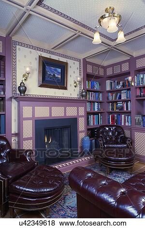 Stock Photo - HOME LIBRARY: Library, basement: Fireplace with wallpaper inset panels, laurel wallpaper borders, coffered and wallpapered ceiling, antique light fixtures, leather chairs. Fotosearch