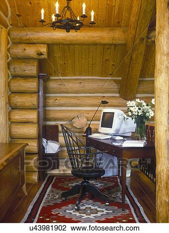 Stock Image - HOME OFFICE - In a new log home, Computer, dark, log walls, wood floor with Southwestern design area rug.. Fotosearch
