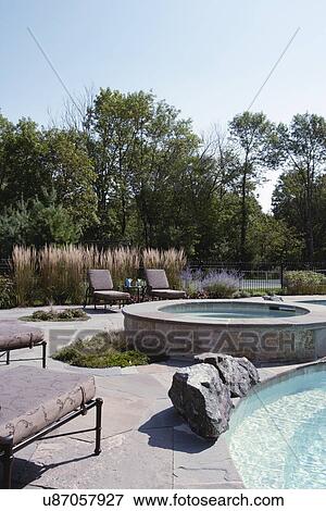 Stock Photo - Hot tub at poolside with lounge chairs. Fotosearch