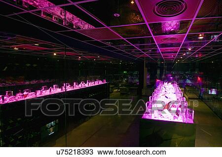 Stock Image - Illuminated pink refrigerated storage with alcohol bottles. Fotosearch