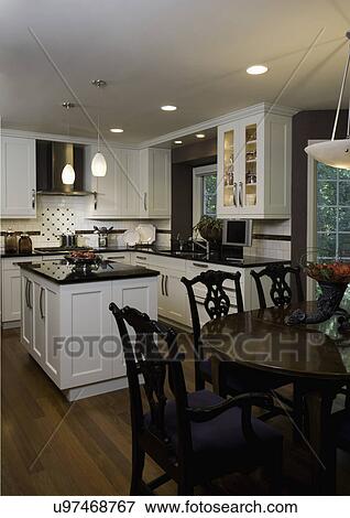 KITCHEN: Contemporary traditional, clean lined dark eggplant colored walls, looking over black oval table with Chinese Chippendale style chairs, sink to right, far side has stainless steel exhaust above tile backsplash View Large Photo Image Stock Photo - KITCHEN: Contemporary traditional, clean lined dark eggplant colored walls, looking over black oval table with Chinese Chippendale style chairs, sink to right, far side has stainless steel exhaust above tile backsplash. Fotosearch