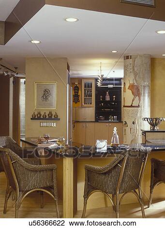KITCHEN -Corner eating area, black counters, wicker chairs, brandy snifters, Egyptian theme, gold painted walls, Egyptian mural on pillar, kitchen in background, recessed lighting, track lighting View Large Photo Image Stock Image - KITCHEN -Corner eating area, black counters, wicker chairs, brandy snifters, Egyptian theme, gold painted walls, Egyptian mural on pillar, kitchen in background, recessed lighting, track lighting. Fotosearch