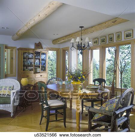 KITCHEN EATING AREAS - Country log beamed ceiling, old Irish pine cupboard, metal elk chandelier, pine floor, twig furniture, French pottery with wild flowers View Large Photo Image Stock Photograph - KITCHEN EATING AREAS - Country log beamed ceiling, old Irish pine cupboard, metal elk chandelier, pine floor, twig furniture, French pottery with wild flowers . Fotosearch