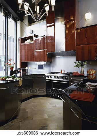 Stock Photograph - Kitchen with contemporary design, stainless steel lower cabinets, and gas stove under the counter flat screen TV. Fotosearch