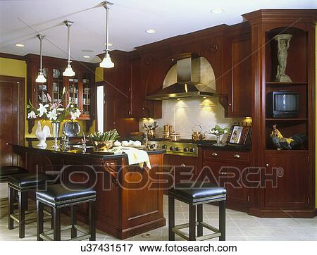 KITCHENS: Cherry cabinets, island with eating bar, stools. Countertops are black marble or granite. Copper pots on stove, ceramic tile floor, stainless steel exhaust hood. With props. View Large Photo Image Stock Photo - KITCHENS: Cherry cabinets, island with eating bar, stools. Countertops are black marble or granite. Copper pots on stove, ceramic tile floor, stainless steel exhaust hood. With props.. Fotosearch