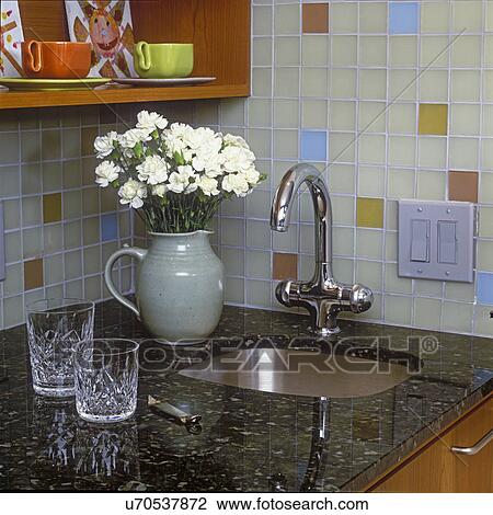 KITCHENS - Color etched-glass tile with matte finish adds dimension to backsplash in bar area. Black granite counter, white flowers, crystal glasses. View Large Photo Image Stock Image - KITCHENS - Color etched-glass tile with matte finish adds dimension to backsplash in bar area. Black granite counter, white flowers, crystal glasses.. Fotosearch