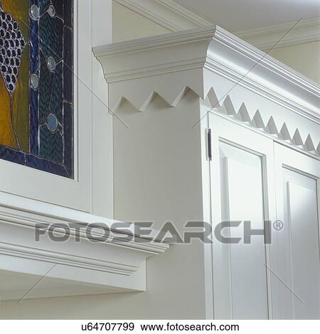 Stock Photo - KITCHENS - Detail of cabinets, saw tooth design that was inspired by antique cupboard. White wood, molding, partial stained glass, architectural detail,. Fotosearch
