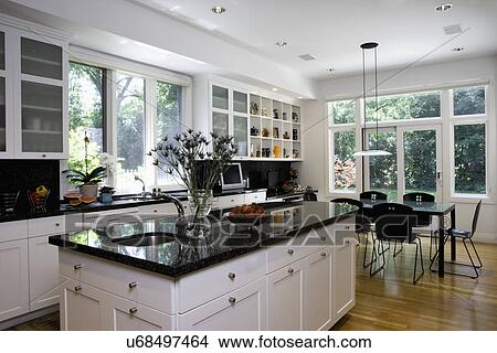 KITCHENS: island in foreground, dark granite, eating area beyond with pendant style light fixture, collection display above desk area, frosted glass cabinet doors, windows over sink area View Large Photo Image Picture - KITCHENS: island in foreground, dark granite, eating area beyond with pendant style light fixture, collection display above desk area, frosted glass cabinet doors, windows over sink area. Fotosearch