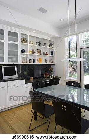 KITCHENS: looking over eating area to kitchen desk area, flat screen TV to left under frosted glass cabinet doors, glass top table contemporary style View Large Photo Image Stock Photograph - KITCHENS: looking over eating area to kitchen desk area, flat screen TV to left under frosted glass cabinet doors, glass top table contemporary style. Fotosearch