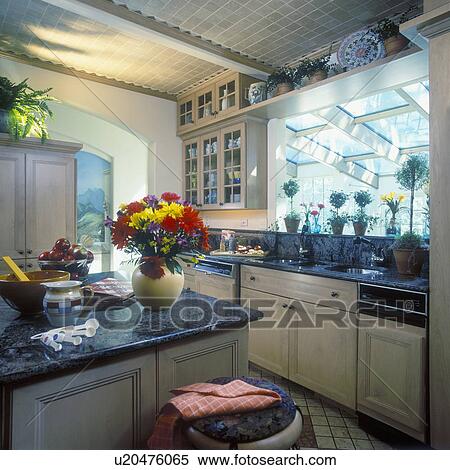 KITCHENS - Overview of kitchen, granite counter tops, light colored wood cabinets with glass front doors, topiary plants on pass thru windows ledge, food preparation, vase of gerberas and mums, topiaries on ledge, vaulted ceiling, looking into sunroom, ti View Large Photo Image Stock Photography - KITCHENS - Overview of kitchen, granite counter tops, light colored wood cabinets with glass front doors, topiary plants on pass thru windows ledge, food preparation, vase of gerberas and mums, topiaries on ledge, vaulted ceiling, looking into sunroom, ti. Fotosearch