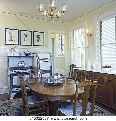 KITCHENS - Restored/revived Victorian home. View towards wall with restored vintage gas stove, white with chrome trim. White subway tile, oval table in foreground. Framed art. View Large Photo Image Stock Photo - KITCHENS - Restored/revived Victorian home. View towards wall with restored vintage gas stove, white with chrome trim. White subway tile, oval table in foreground. Framed art.. Fotosearch
