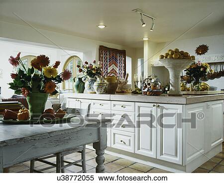 KITCHENS: white cabinetry, cement countertops, French pottery, colorful floral arrangements of zinnias and roses, large terra cotta vase filled with oranges, tile floor, farm table, View Large Photo Image Stock Photography - KITCHENS: white cabinetry, cement countertops, French pottery, colorful floral arrangements of zinnias and roses, large terra cotta vase filled with oranges, tile floor, farm table,. Fotosearch