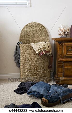 Stock Image - Laundry on carpet outside wicker basket, San Diego, California, United States of America. Fotosearch