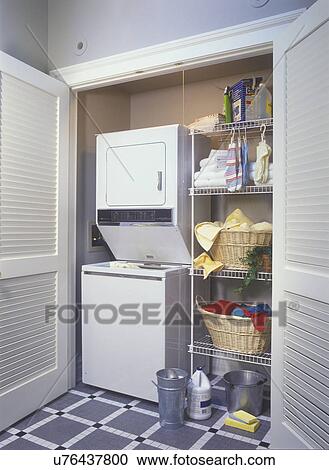 LAUNDRY ROOMS: Closet laundry area in garden room off kitchen. Stacked washer and dryer, gray and white ceramic tile floor, wire shelves with cleaning supplies View Large Photo Image Stock Image - LAUNDRY ROOMS: Closet laundry area in garden room off kitchen. Stacked washer and dryer, gray and white ceramic tile floor, wire shelves with cleaning supplies. Fotosearch