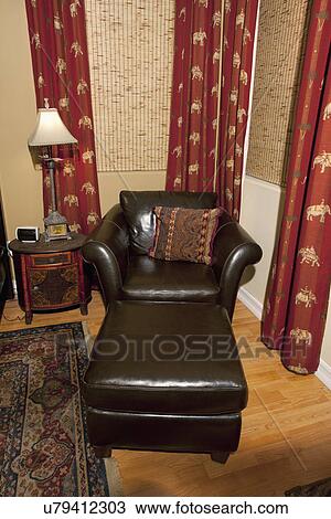Stock Image - Leather armchair and ottoman in corner, Laguna Beach, California, USA. Fotosearch