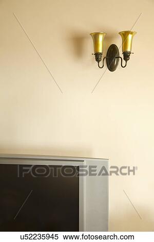 Stock Photography - Light sconce on the wall above TV; Carpinteria; California; USA. Fotosearch