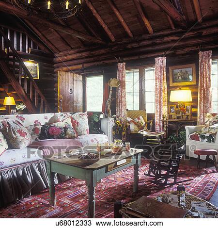 LIVING ROOM - Log home, log walls and ceiling, country furnishings, cabin style, Kilim rug, child's rocker, vintage fabrics, bark cloth, shortened farm table as a coffee table, slip covered sofa, toile drapes, cottage, rustic View Large Photo Image Stock Image - LIVING ROOM - Log home, log walls and ceiling, country furnishings, cabin style, Kilim rug, child's rocker, vintage fabrics, bark cloth, shortened farm table as a coffee table, slip covered sofa, toile drapes, cottage, rustic . Fotosearch
