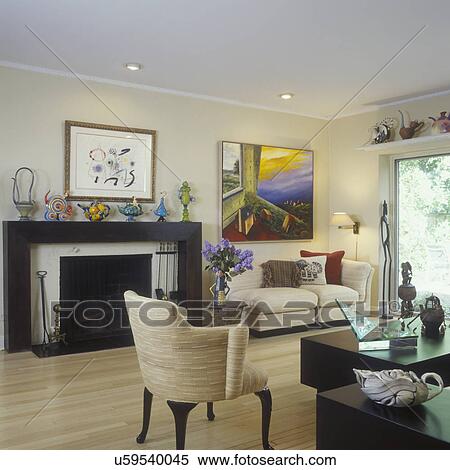Stock Photography - LIVING ROOMS - Modern, eclectic, lots of original art, framed art on wall, artsy teapot collection. Fireplace with one of a kind teapots on display. Beige tones. . Fotosearch
