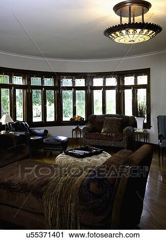 LIVING ROOMS: rounded bay of windows, stained glass at top, earthy masculine, brown chaise in foreground View Large Photo Image Stock Image - LIVING ROOMS: rounded bay of windows, stained glass at top, earthy masculine, brown chaise in foreground. Fotosearch