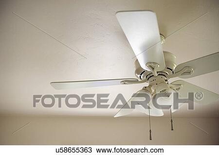 Stock Image - Low angle view of a ceiling fan with lights. Fotosearch