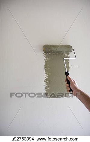 Picture - Male hand painting with paint roller on wall. Fotosearch