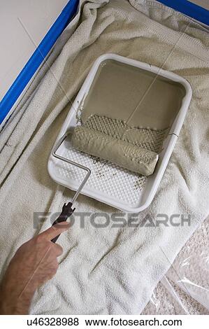 Stock Photo - Male hand picking paint roller from tray. Fotosearch