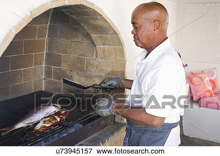 Man cooking fish on indoor grill, Mykonos, Greece View Large Photo Image Stock Photo - Man cooking fish on indoor grill, Mykonos, Greece. Fotosearch