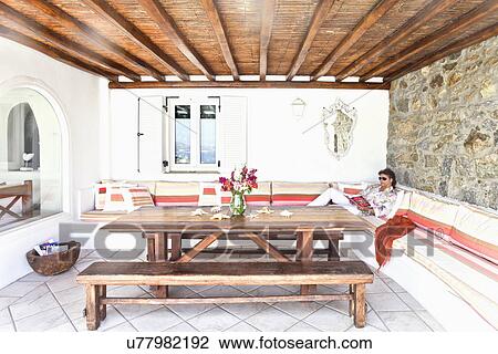 Man reading on bench in Greek dining room, Mykonos, Greece View Large Photo Image Stock Image - Man reading on bench in Greek dining room, Mykonos, Greece. Fotosearch