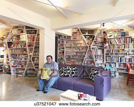 Stock Photo - Man sitting on purple sofa in apartment home; Taipei; Taiwan. Fotosearch