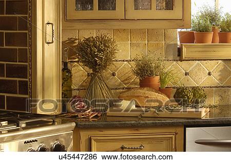 Stock Photograph - Meat with loaf of bread and artichoke on kitchen counter. Fotosearch