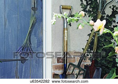 Stock Image - Outbuildings - Potting shed: Various detail shots of mural painted on outside of shed. Blue door with faux painting of shovel and vines.. Fotosearch