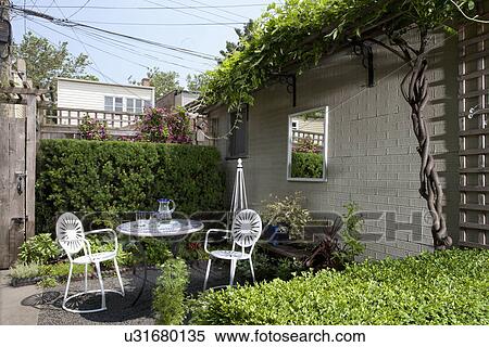 Stock Photography - Outdoor table and chair in back yard garden of residential structure. Fotosearch