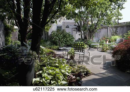 PATIO AREA: Fenced city garden and patio, trees to left, stone patio with flower borders surrounding, garage to back of lot with lattice View Large Photo Image Stock Photography - PATIO AREA: Fenced city garden and patio, trees to left, stone patio with flower borders surrounding, garage to back of lot with lattice. Fotosearch