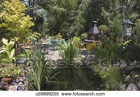 Stock Photography - PATIO AREA: pond in foreground, dining area beyond with outdoor fireplace. Fotosearch