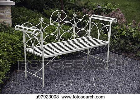 PATIO: close up of metal scroll armed garden bench on crushed grey rock, shaped hedges behind View Large Photo Image Stock Photo - PATIO: close up of metal scroll armed garden bench on crushed grey rock, shaped hedges behind. Fotosearch
